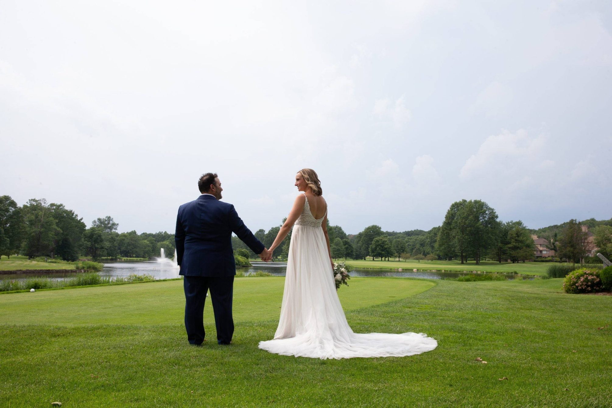 Brooklake bride and groom holding hands by the lake
